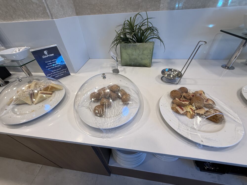 ドーム型のカバーの中に置かれたサンドイッチ類や、一口サイズの軽食が並ぶテーブル。