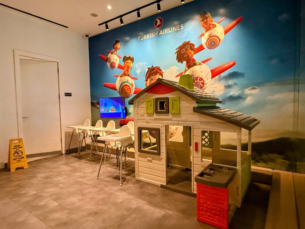 ターキッシュエアラインズ国内線ラウンジのキッズルーム。おままごとハウスとベビーチェア、アニメが流れるテレビ