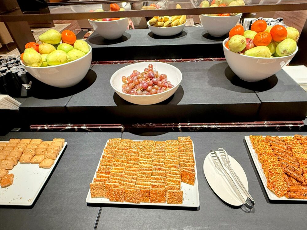 ビュッフェカウンターに並ぶ新鮮なフルーツのボウルと、クッキーやスナック類