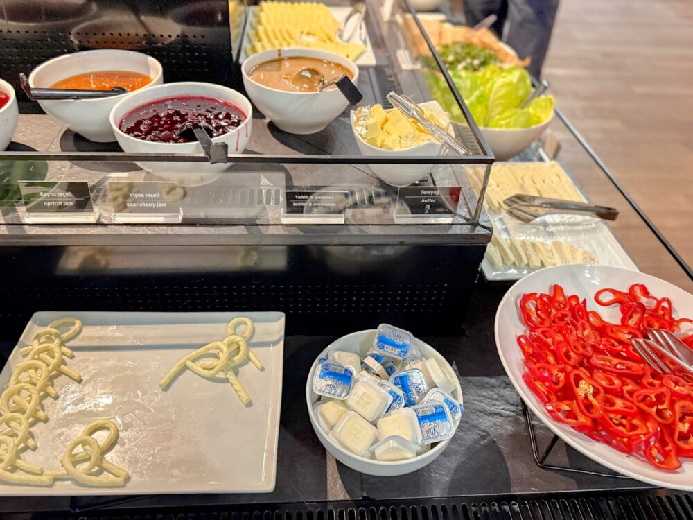 ジャムやバター、チーズ、スライスされた赤パプリカが並ぶビュッフェの朝食・軽食エリア