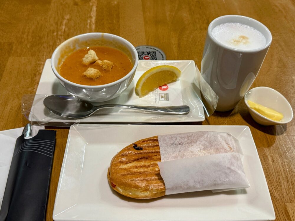 スープ、温かいパニーニ、飲み物、バターがセットされた機内食風の食事セット