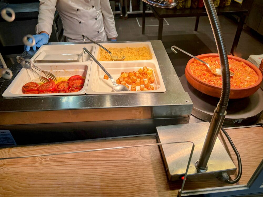 シェフがライブキッチンで調理している、トマトやポテトなどの温かい料理