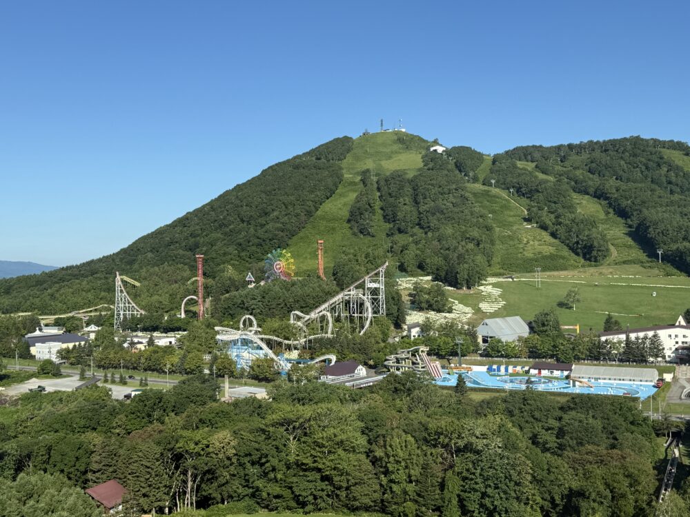 ウェスティンルスツリゾートの高層階から見た、夏のルスツリゾート遊園地と緑の山