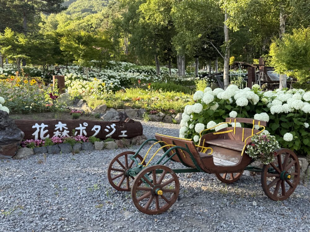 ルスツリゾートの庭園「花森ポタジェ」の看板と、花を飾った木製の馬車