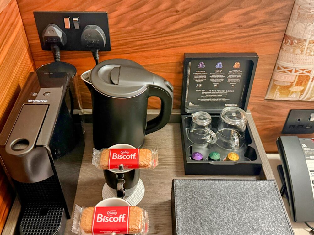 客室内のコーヒーメーカー、電気ケトル、カプセル、ロータスビスケットが並ぶドリンクコーナー