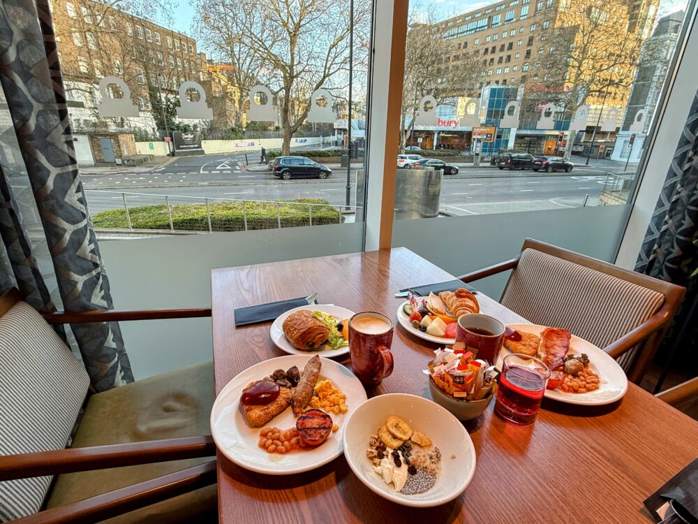 窓際の特等席にセッティングされた豪華な朝食メニューと、外に見えるロンドンの街並み