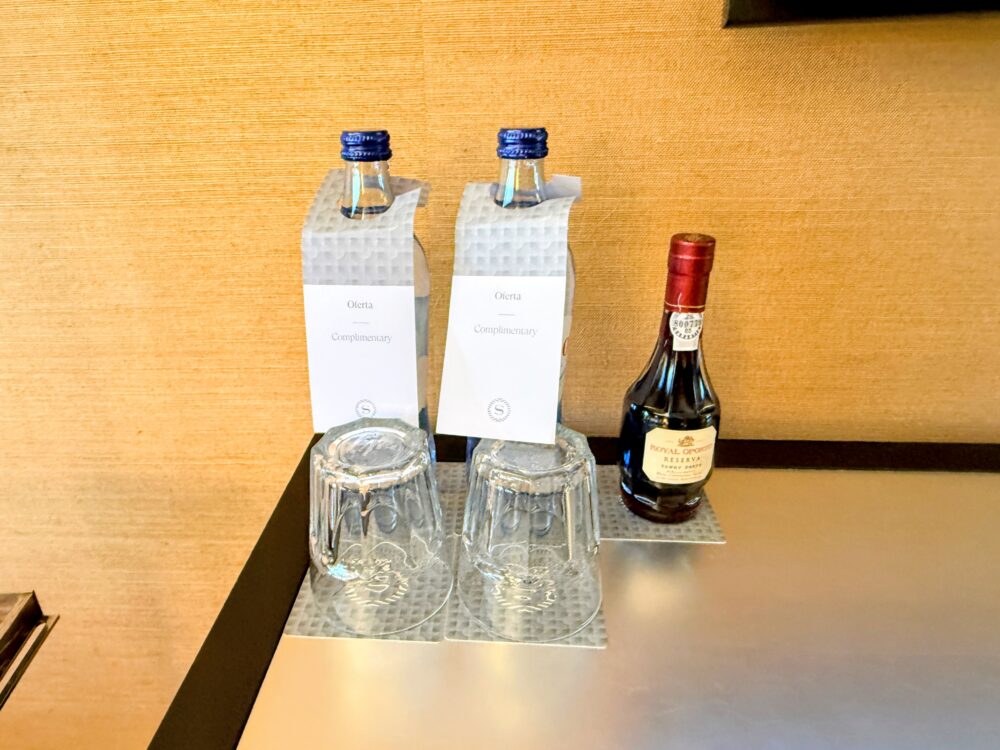 チェスト上に置かれた無料のミネラルウォーター(Complimentary)とミニボトルのポートワイン