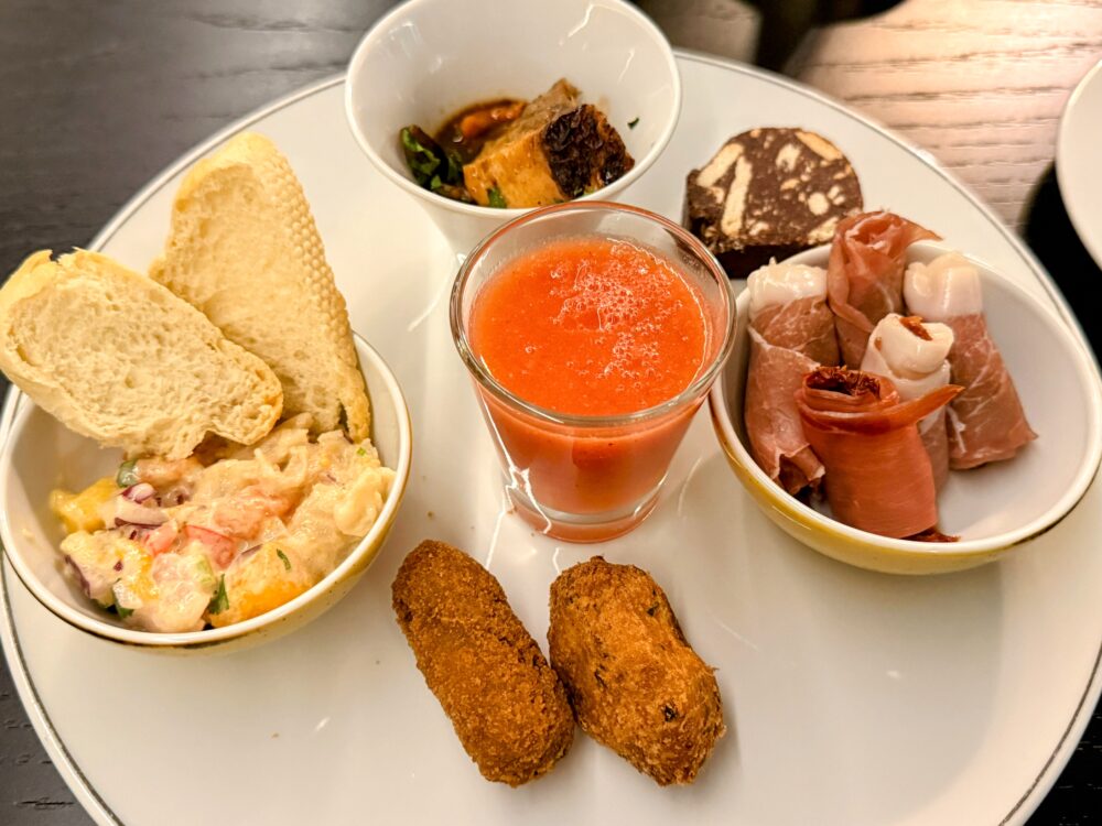 パン、生ハム、サラダ、スープ、コロッケ、デザートなどが彩りよく盛られたプレート
