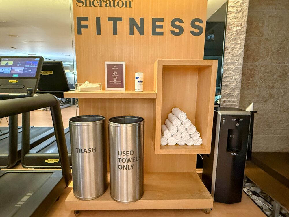 「Sheraton FITNESS」のロゴが掲げられたタオル、ゴミ箱、給水器のステーション