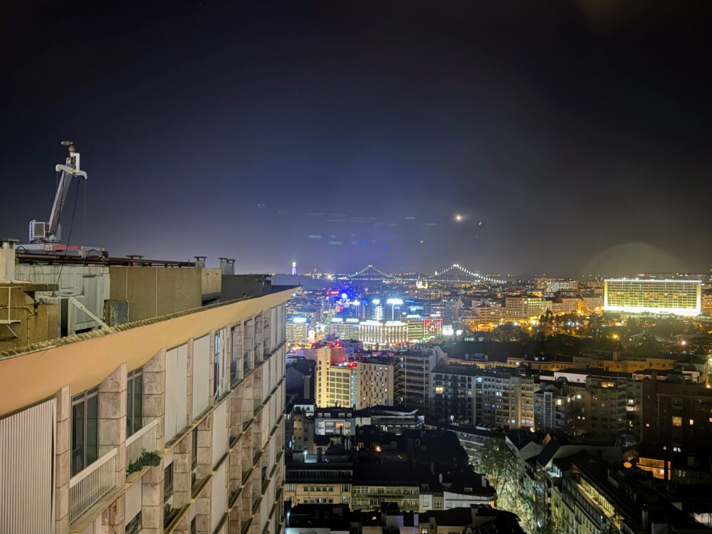ホテルの客室から望む、夜景に輝くリスボンの街並みと遠方の橋の景色