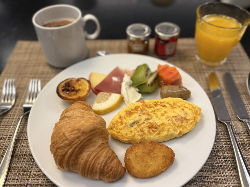 クロワッサン、エッグタルト、オムレツ、フルーツなどがバランスよく盛られた朝食プレート