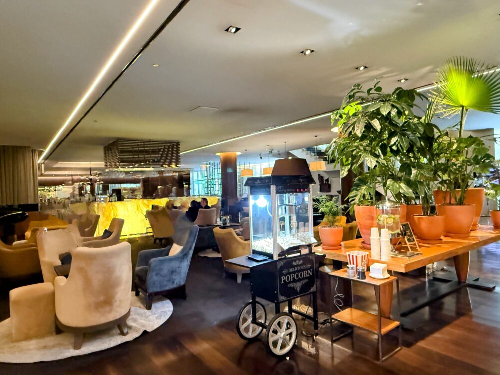 ポップコーンマシンや観葉植物、ソファセットが配置されたホテルの広々としたロビーラウンジ