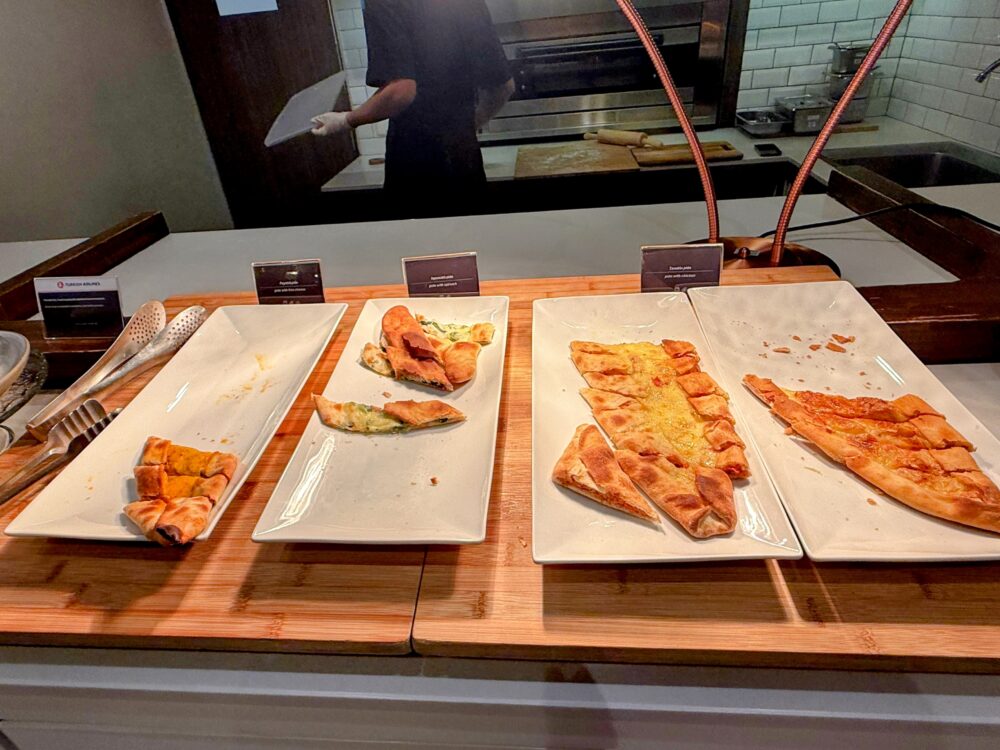 ターキッシュエアラインズ ラウンジのビュッフェカウンターに並ぶ焼き立てのピデ(トルコ風ピザ)各種