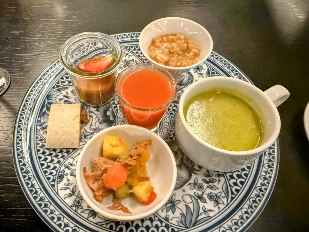 スープ、サラダ、デザート、ジュースなどの小皿料理が美しい大皿にバランスよく並べられたメニュー