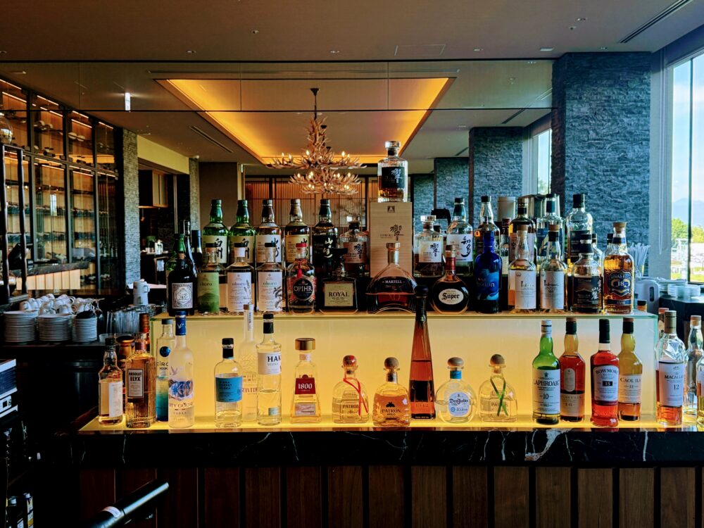 ホテルのバーカウンターにずらりと並ぶ多彩な洋酒やウイスキー、リキュールのボトル。上段には「響」のボトルが飾られている。
