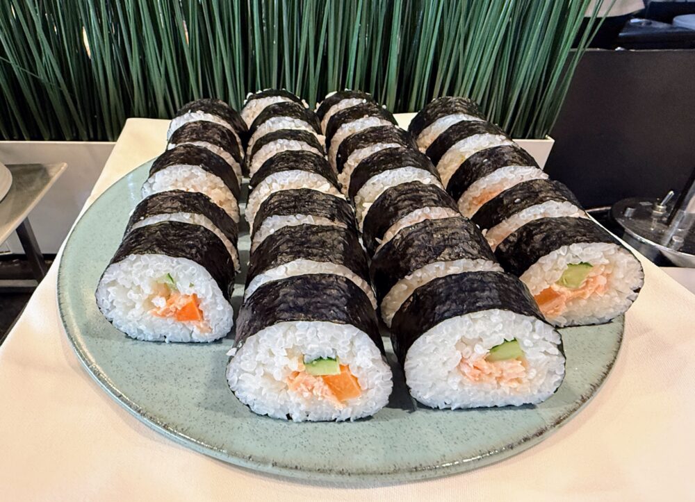 朝食ビュッフェの巻き寿司。サーモンときゅうりが入った細巻きが、水色の丸いお皿に盛り付けられている。