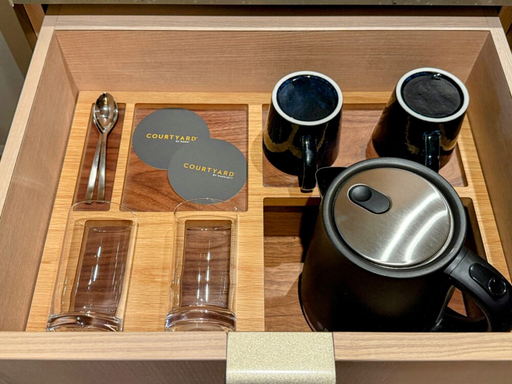 客室の引き出しを開けた様子。中に黒いマグカップ、電気ケトル、グラス、コースター、スプーンが綺麗に収納されている。