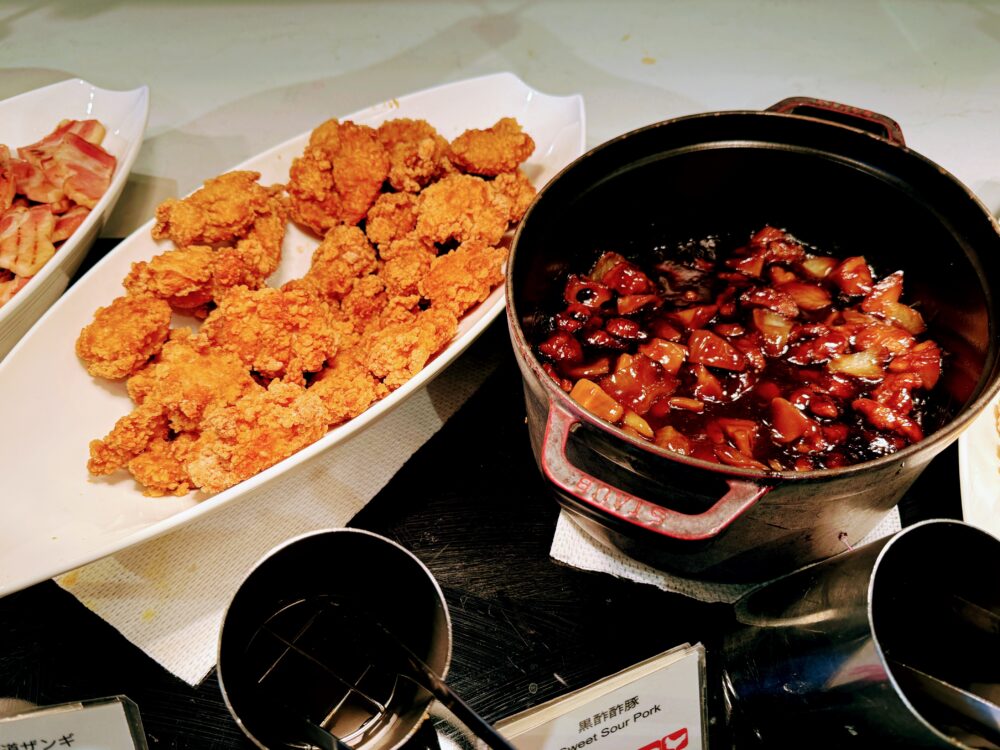白い大皿に山盛りにされた「道産ザンギ（鶏の唐揚げ）」と、STAUBの鍋に入った「黒酢酢豚」。