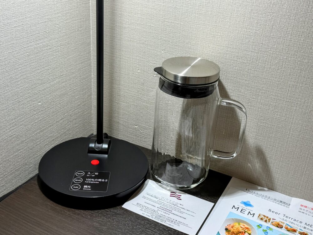 デスク上のガラス製のウォーターポットと調光式デスクライト