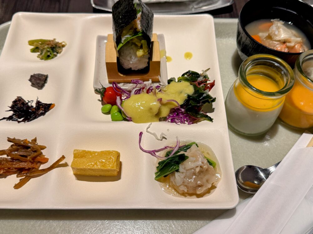 ANAクラウンプラザホテル札幌の朝食を盛り付けたプレート。おむすび、サラダ、焼売、郷土汁、スムージー2種