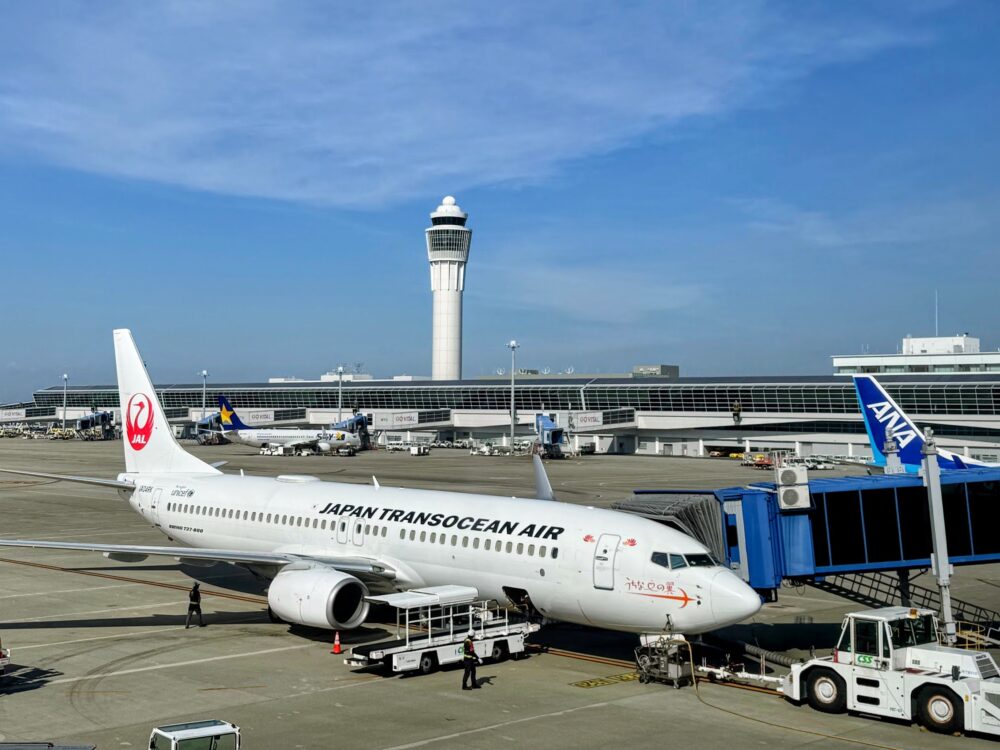 JALグループの日本トランスオーシャン航空(JTA)のボーイング737-800「うちなーの翼」。奥に管制塔とANAの搭乗橋が見える。