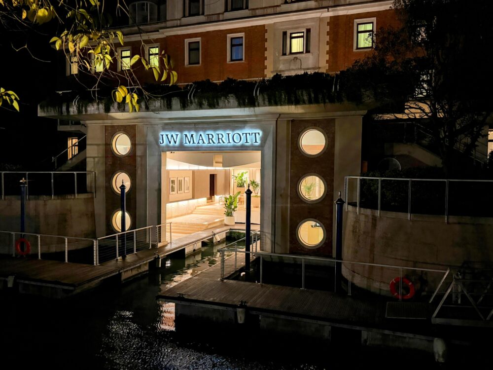 夜のJWマリオット・ベニスの水上エントランス。「JW MARRIOTT」のロゴが白くライトアップされ、水面に建物の明かりが反射している