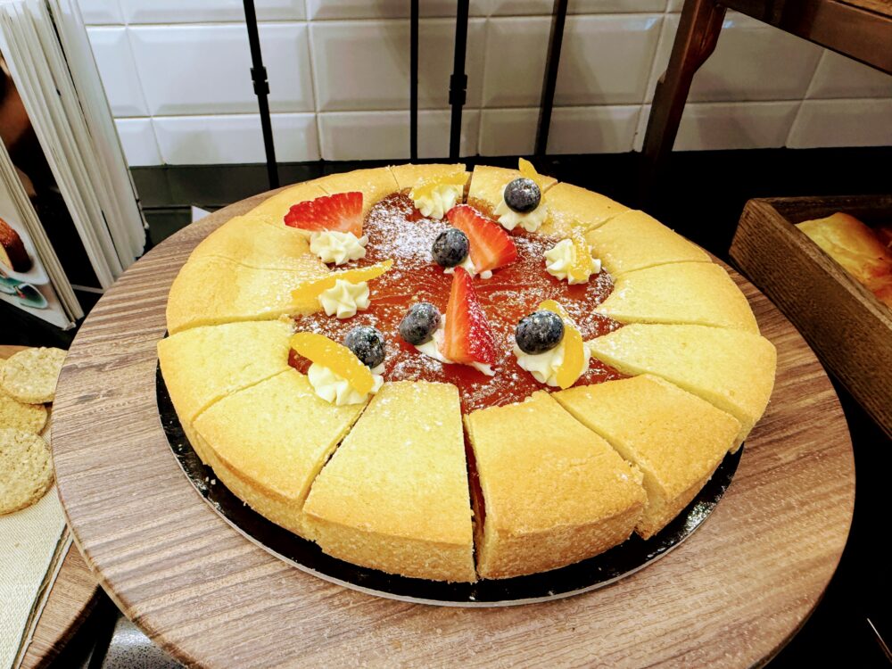 朝食ビュッフェのスイーツコーナー。イチゴ、ブルーベリー、オレンジピールで美しくデコレーションされた、大きなホールケーキ（タルト）