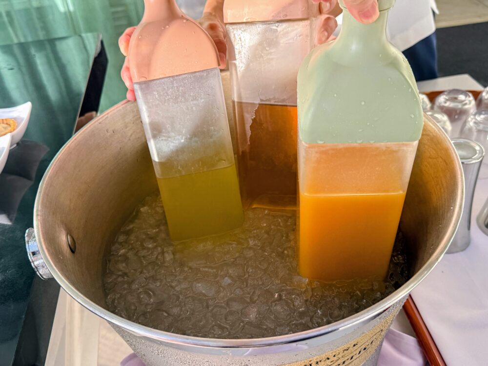 氷を入れたバケツで冷やされた、オレンジなどのソフトドリンクのボトル。