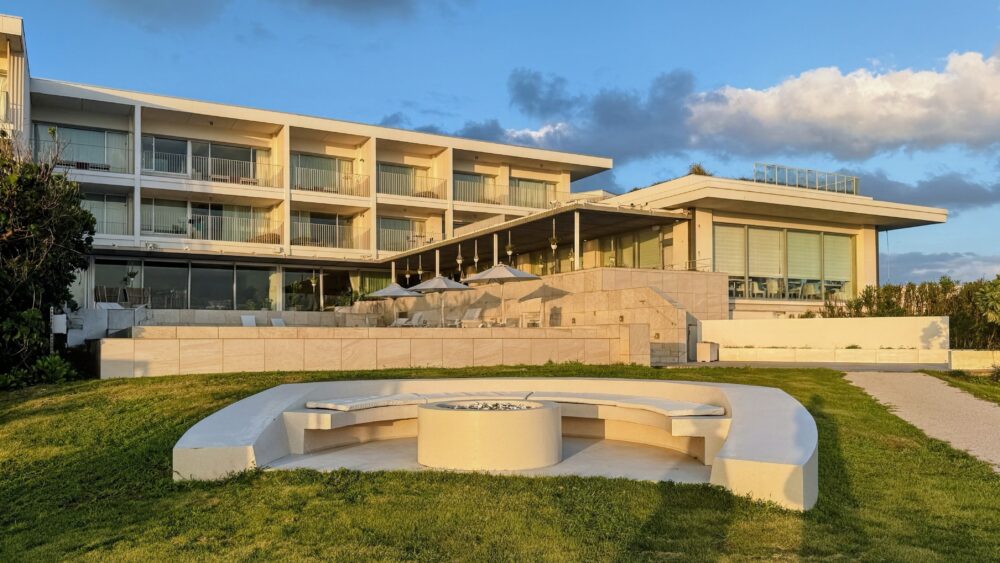 芝生の中央にある円形のベンチと、その奥に建つイラフSUIの客室棟。