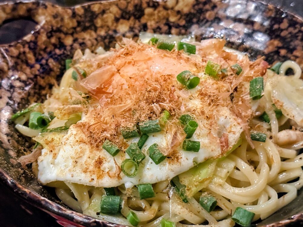 目玉焼きと鰹節をのせた麺料理。