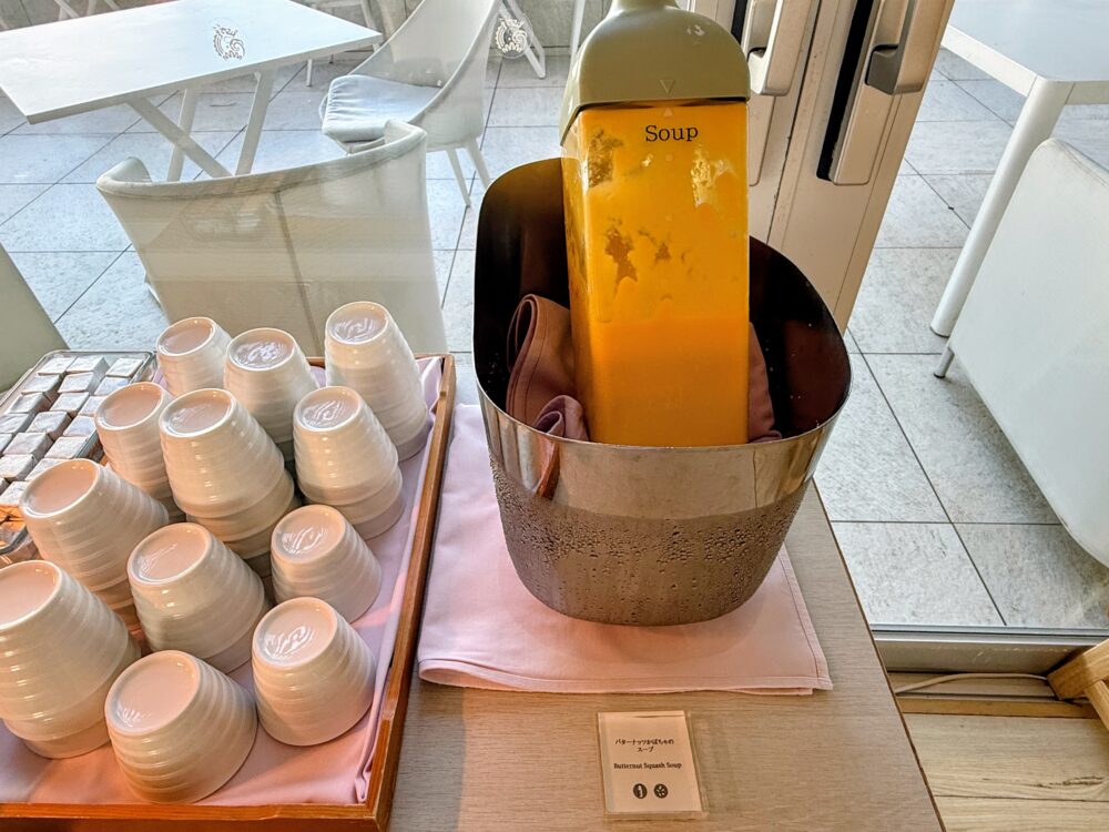 保温ジャーに入ったオレンジ色のスープと、スープカップ。