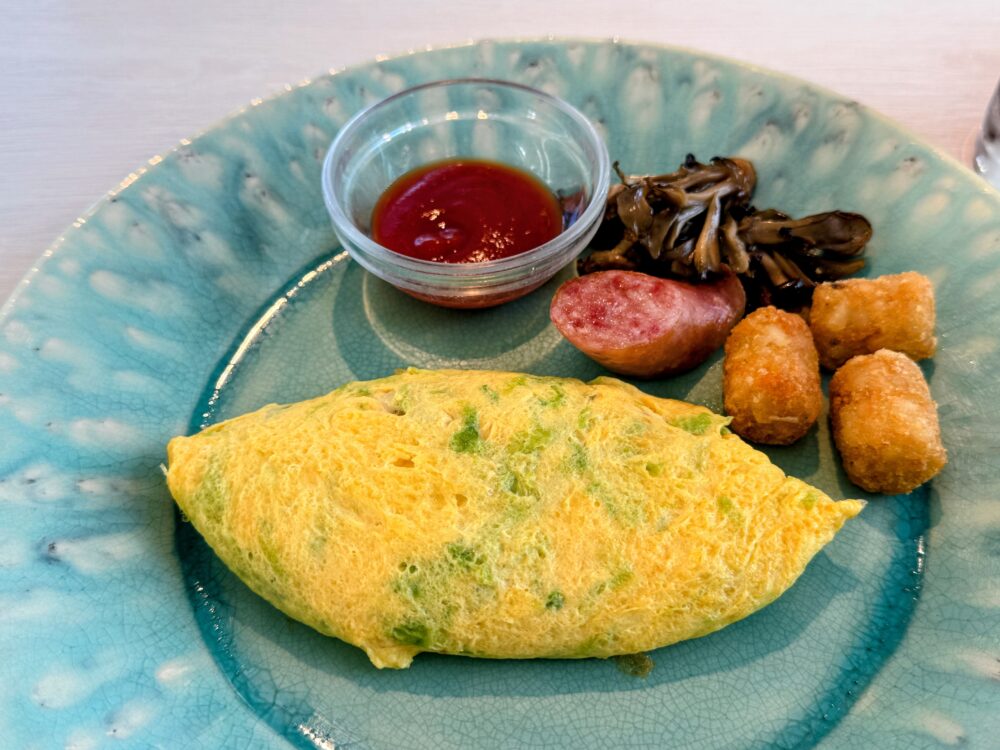 洋食メインのオムレツ。宮古ソーセージ、ポテト、きのこソテー、ケチャップが添えられている。