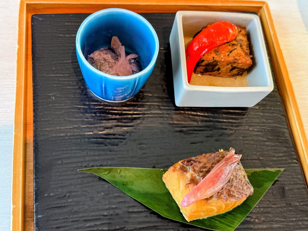 和食の小鉢2種と、葉の上に盛られた魚料理。