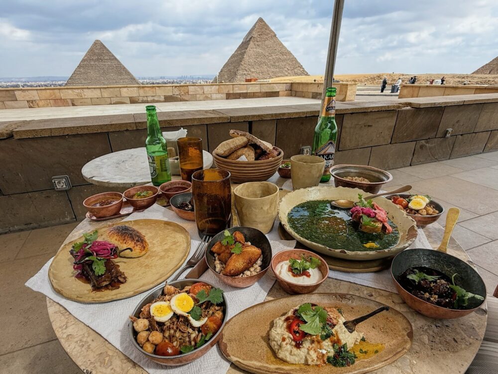 ピラミッドを望むKhufu's Restaurantのテラス席と、テーブルに並んだランチのセットメニュー